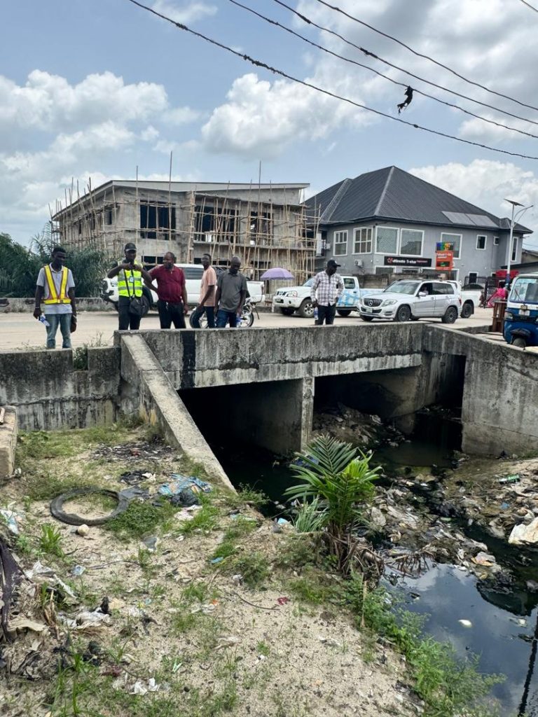 Priority intervention zone requiring immediate emergency desilting. The complete blockage beneath this bridge structure represents a critical flood risk requiring mechanical excavation. Estimated waste volume: 15-20 cubic meters requiring removal and proper disposal.